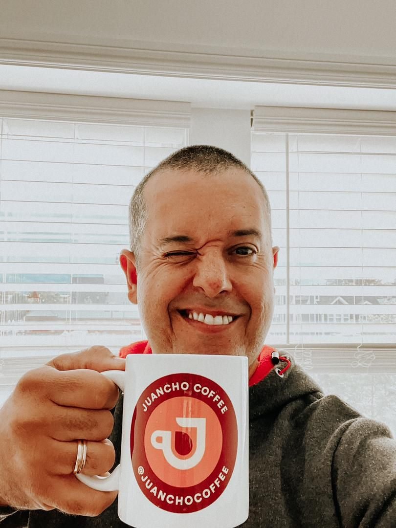 Juancho guiñando un ojo con su taza de Juancho Coffee