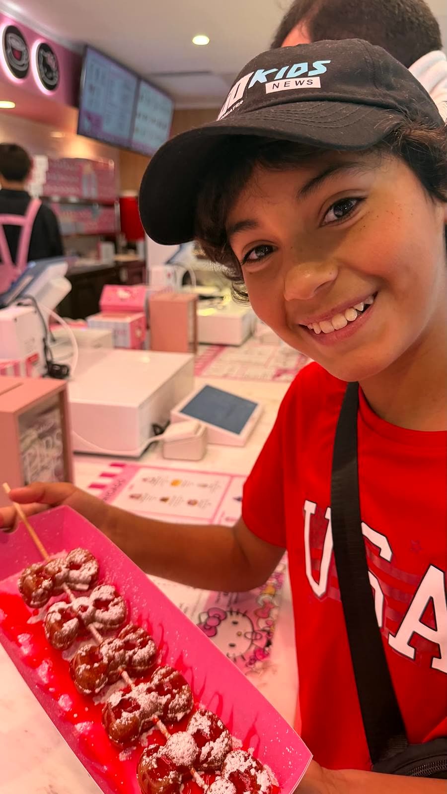 Niño feliz con una bandeja de Bow Waffles con sirope de fresa en el Hello Kitty Cafe